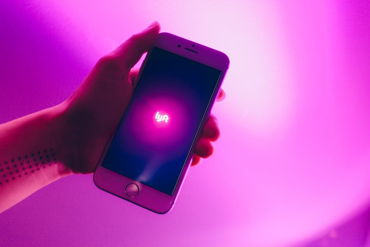 Person holding phone with Lyft app open for rideshare and delivery side hustle