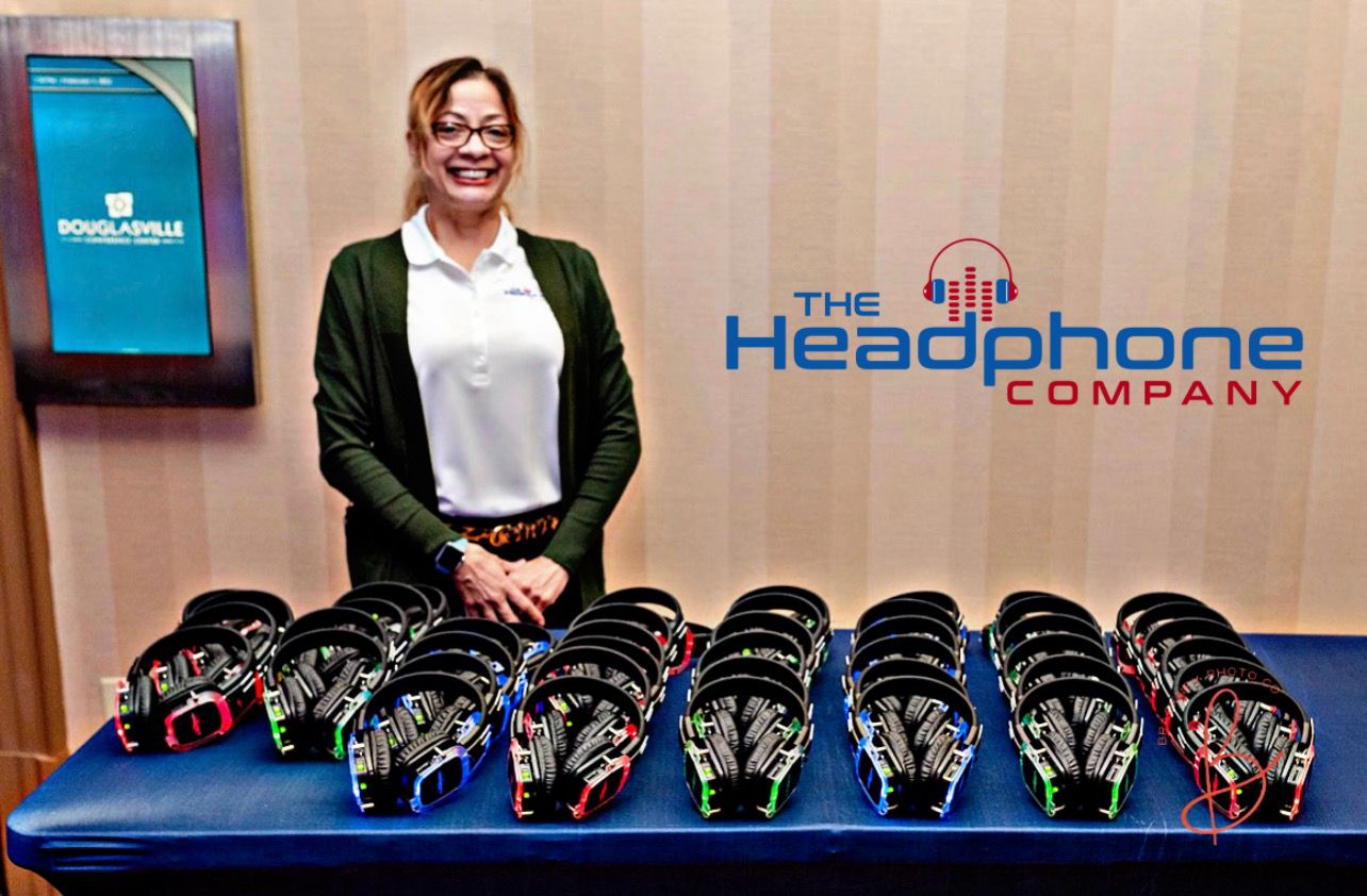 The Headphone Company event display with rows of illuminated headphones and a woman standing behind the table